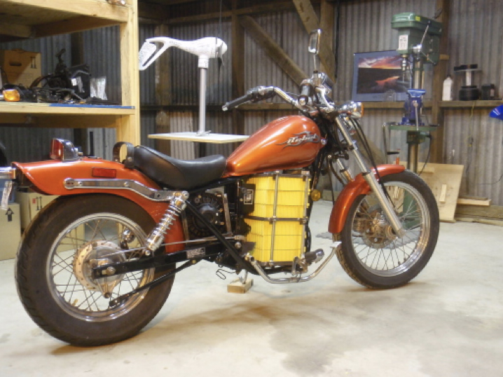 Finished orange custom electric Honda Rebel with yellow battery pack mounted in the frame